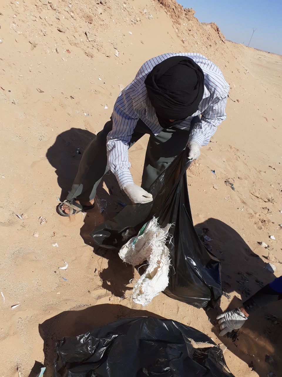 Ein Mann sammelt Müll in einer Plasiktüte auf.