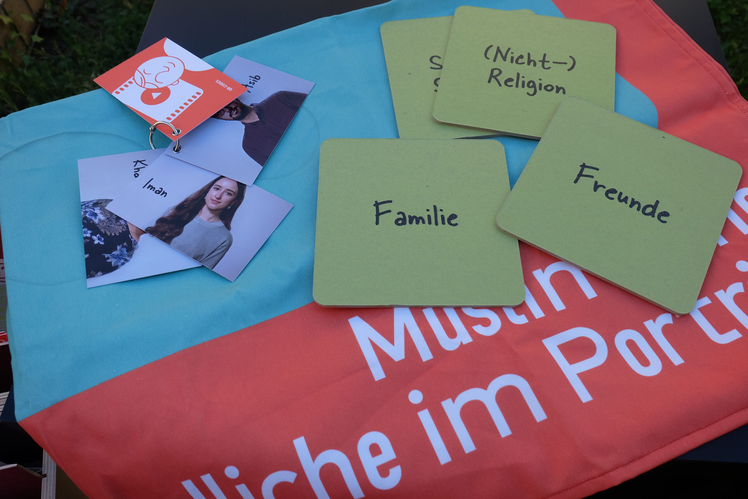 Bilder und Kärten liegen auf einem Tuch. Auf den Karten stehen Wörter, z.B. Familie, Freunde, Nicht-Religion