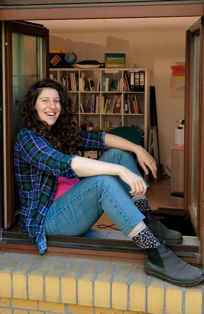 Junge lachende Frau sitzt am offenen Fenster